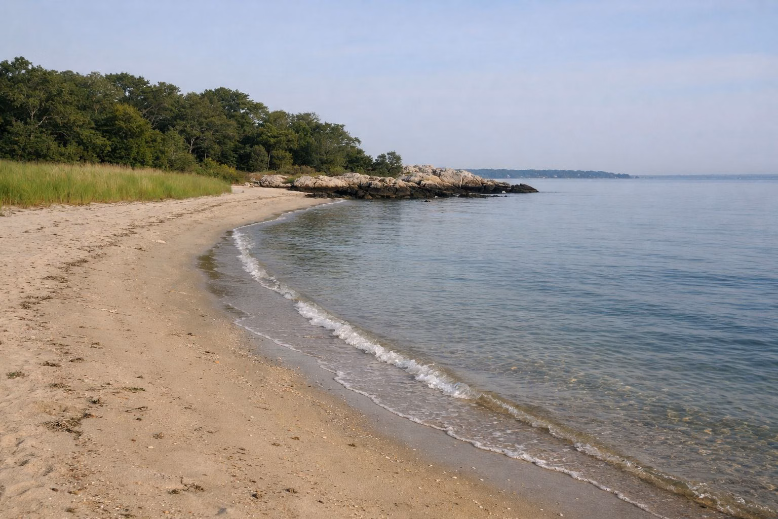 Gently sloping sandy beach and calm clear water on a summer morning