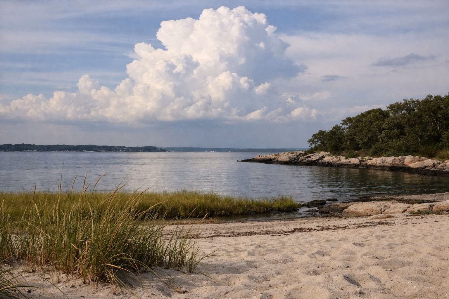 Summer clouds building over calm water seen from a sandy beach