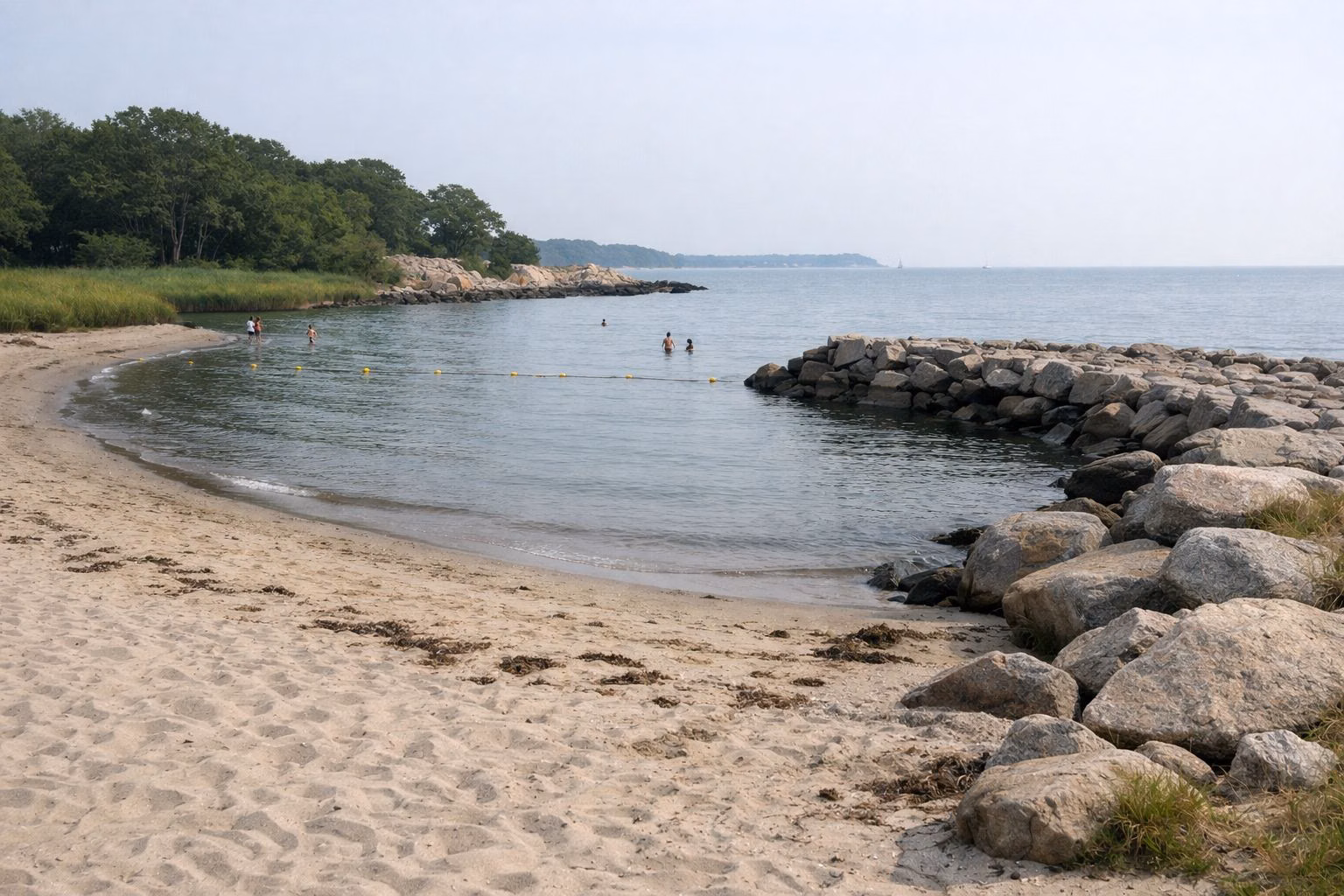 Small sandy cove beach beside a low stone jetty